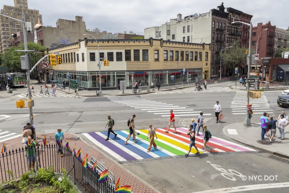 Pedestrians crossing a rainbow painted crosswalk in New York City.